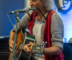 Andrea Angelini grający na gitarze i harmonijce, widok z boku (photo)