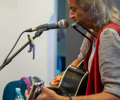 Andrea Angelini grający na gitarze i harmonijce, widok z boku (photo)