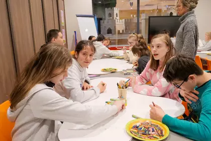 Uczniowie pracują przy stole, tworząc ilustracje inspirowane tekstem.