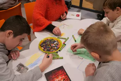 Dzieci rysują i kolorują wspólną pracę plastyczną.