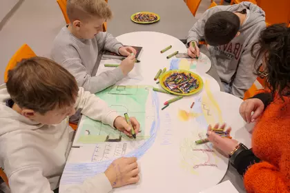 Uczniowie pochylają się nad rysunkami, pracując w skupieniu.