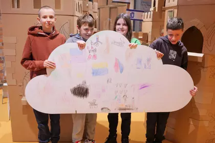 Uczniowie trzymają wspólną ilustrację wykonaną podczas warsztatów.