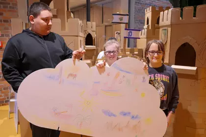 Uczniowie stoją z dużą ilustracją stworzoną na zajęciach.