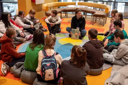 Grupa siedzi w kręgu na dywanie podczas podsumowania warsztatów.