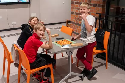 Dzieci grają w gry planszowe przy stoliku w bibliotece.