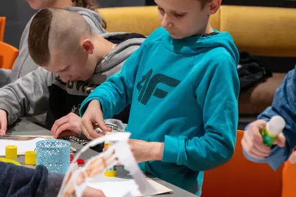 Dziecko wycina elementy pracy plastycznej podczas warsztatów.