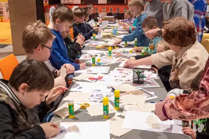 Rodzinne warsztaty plastyczne w bibliotece, dzieci skupione na pracy.