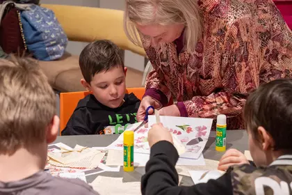 Babcia pomaga wnukowi przy pracy plastycznej podczas warsztatów.