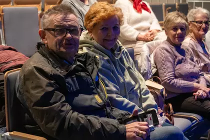 Uczestnicy siedzą w sali i oglądają film.