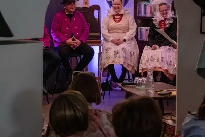 Artyści siedzą na scenie przed publicznością.