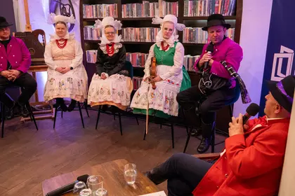 Artyści siedzą na scenie podczas spotkania z publicznością.