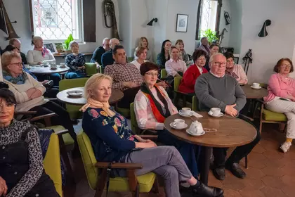 Publiczność siedzi przy stolikach i ogląda występ.