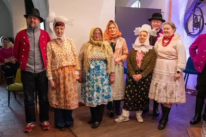Grupa osób w ludowych strojach pozuje do wspólnego zdjęcia.