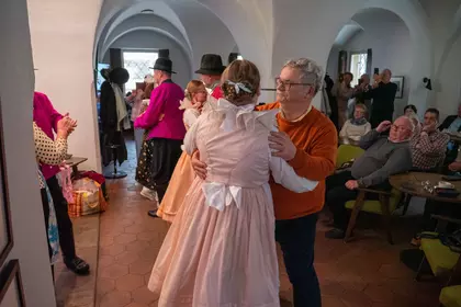 Kobieta w jasnej sukni tańczy z partnerem w sali bibliotecznej.