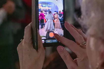 Osoba fotografuje tańczącą parę telefonem komórkowym.