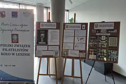 Plansze z eksponatami filatelistycznymi ustawione na sztalugach w bibliotece.