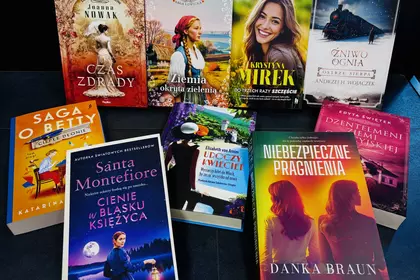 Kolorowe okładki powieści ustawione na stole bibliotecznym.