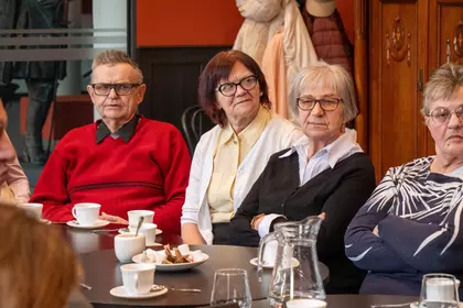 Seniorzy siedzą przy stoliku podczas bibliotecznego spotkania.
