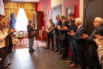 Uczestnicy wydarzenia biją brawo w sali z historycznym wystrojem.