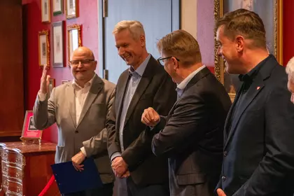 Grupa mężczyzn stoi obok siebie i uśmiecha się podczas spotkania.