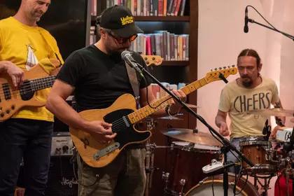 Muzycy grają na gitarze i perkusji podczas koncertu.
