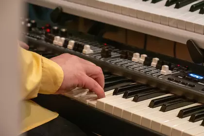 Zbliżenie na dłonie muzyka grającego na instrumentach klawiszowych.