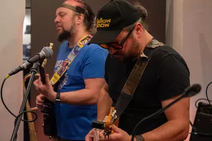 Dwóch muzyków śpiewa i gra na gitarach podczas występu.