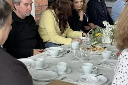 Grupa uczestników rozmawia podczas spotkania przy kawie i poczęstunku.