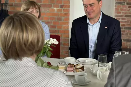 Prezydent Leszna Grzegorz Rusiecki siedzi przy stole podczas spotkania w bibliotece.