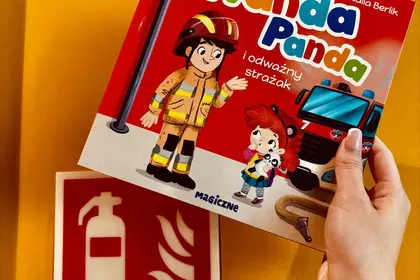 Książka „Wanda Panda i odważny strażak” trzymana przy znaku gaśnicy