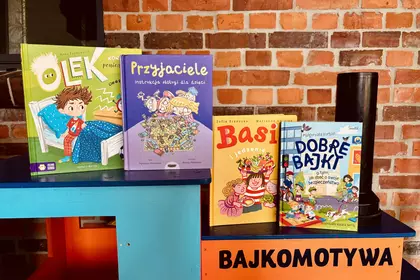 Książki dla dzieci ustawione na kolorowej „Bajkomotywie”