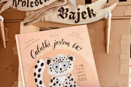 Książka „Całkiem jestem OK” trzymana przed kartonowym zamkiem