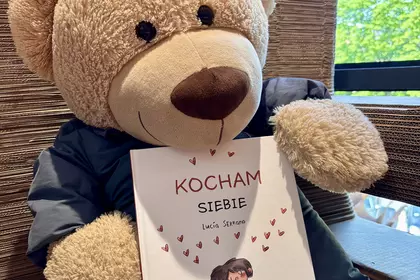 Pluszowy miś trzymający książkę „Kocham siebie”
