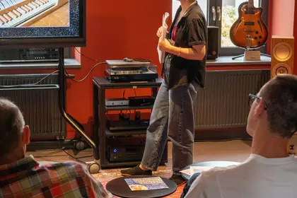 Prowadząca opowiada o historycznych instrumentach klawiszowych podczas spotkania muzycznego.