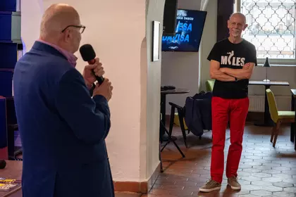 Uczestnik w koszulce „Miles” słucha prowadzącego podczas jazzowego spotkania.