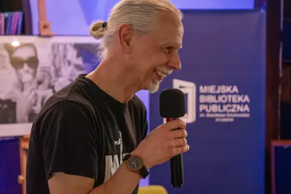 Mężczyzna z mikrofonem opowiada o Milesie Davisie w bibliotece.