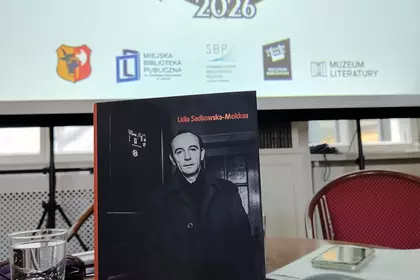 Książka „Menuet z Grochowiakiem” na tle ekranu Roku Grochowiaka w Lesznie