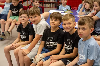 Grupa dzieci podczas spotkania i wspólnych zabaw w bibliotece.