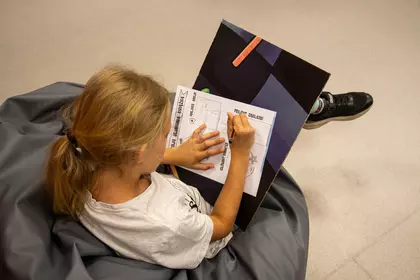 Dziewczynka uzupełnia kartę pracy podczas zajęć bibliotecznych.