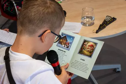 Chłopiec czyta książkę do mikrofonu.