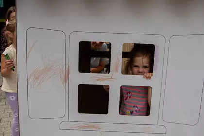 Dziecko wygląda przez okno kartonowego domku.