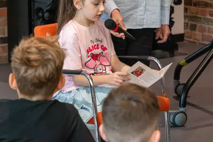 Uczennica czyta fragment książki podczas spotkania autorskiego