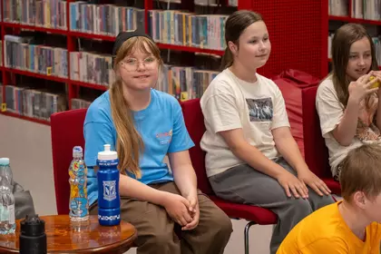 Dzieci uczestniczą w zajęciach czytelniczych w bibliotece.