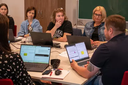 Grupa bibliotekarzy słucha prowadzącego podczas warsztatów komputerowych.