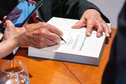Autor składa dedykację w książce podczas podpisywania egzemplarzy.