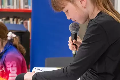 Dziewczynka czyta do mikrofonu podczas akcji „Jak nie czytam, jak czytam”.