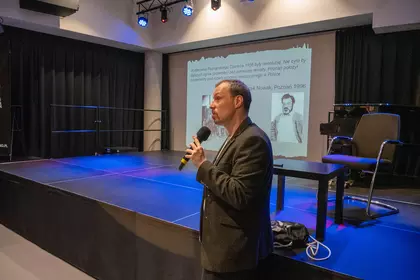 Prelegent omawia wydarzenia historyczne na tle prezentacji multimedialnej.