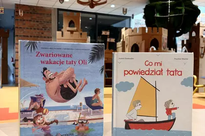 Książki „Zwariowane wakacje taty Oli” i „Co mi powiedział tata” wyeksponowane w bibliotecznej przest