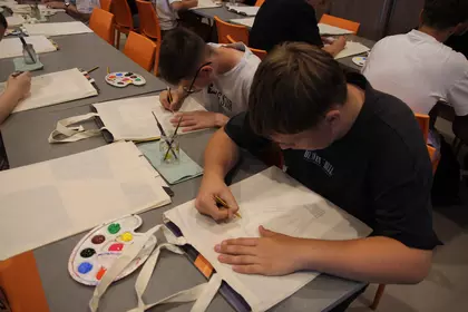 Uczniowie wspólnie pracują nad ozdabianiem materiałowych toreb.