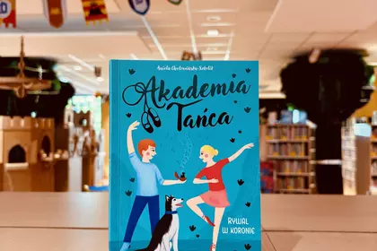 Książka „Akademia Tańca. Rywal w koronie” ustawiona na stole w Oddziale dla Dzieci i Młodzieży.